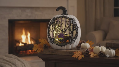 A slow cinematic zoom video of a lighted white resin pumpkin decoration glowing on a fireplace mantel at night, highlighting the intricate details of the internal miniature witch and bubbling cauldron scene.